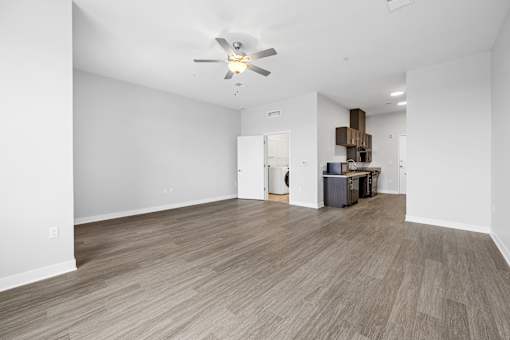 A room with a ceiling fan and light fixture, and a wooden floor.