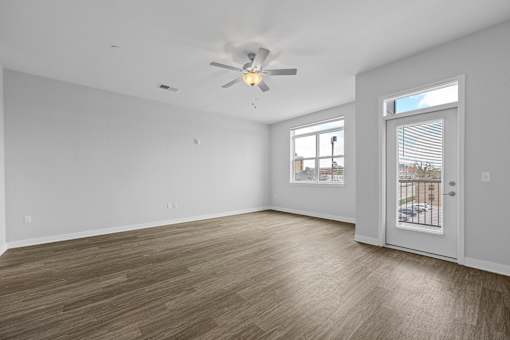 A room with a ceiling fan and a door leading to a balcony.