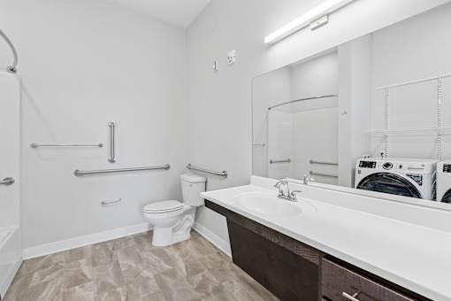 A white bathroom with a toilet, sink, and a washing machine in the corner.
