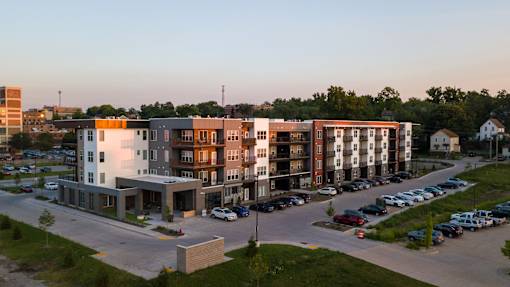 A modern apartment complex with a parking lot in front.