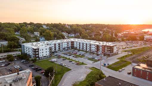 A sunset view of a large apartment complex with a parking lot in front.