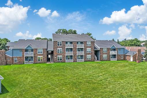 A large brick building with a green lawn in front.