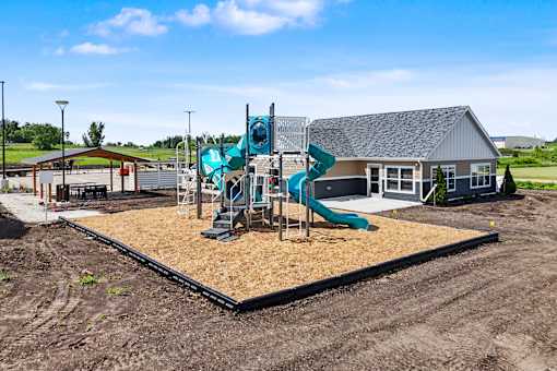 A playground with a slide and a building in the background.