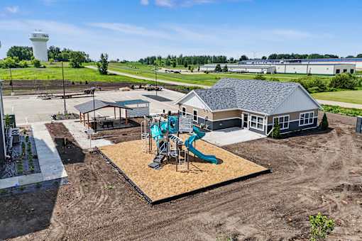 A playground with a blue slide is in the foreground of a construction site.