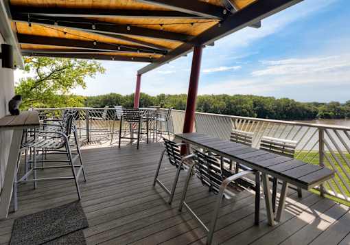 A wooden deck with tables and chairs overlooking a grassy area. at Eagle View Lofts, Iowa