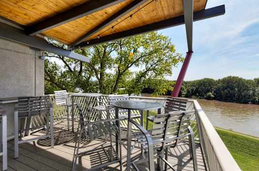 A patio with chairs and a table overlooking a river. at Eagle View Lofts, Des Moines, Iowa