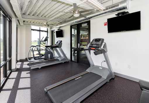 A gym with treadmills and a television mounted on the wall. at Eagle View Lofts, Iowa