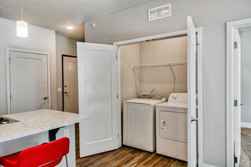 A small kitchen with a red chair and white cabinets.
