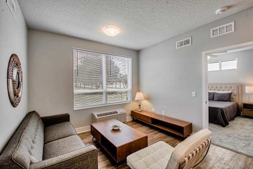 A living room with a couch, chair, and a table with a lamp on it.