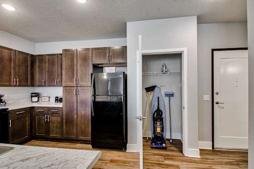A kitchen with a black fridge and wooden cabinets.