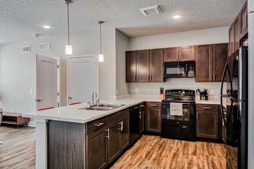 A kitchen with dark wood cabinets and a black refrigerator.