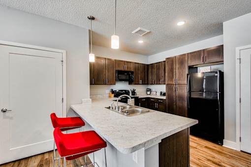A kitchen with a white countertop and red chairs.