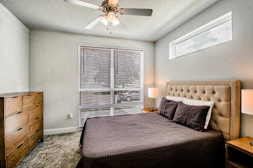 A bedroom with a bed, dresser, and window.