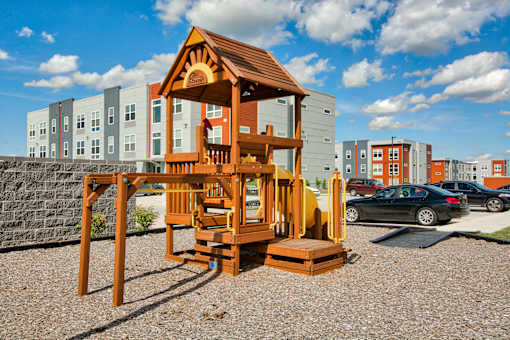 A wooden playhouse sits in the foreground of a residential area.