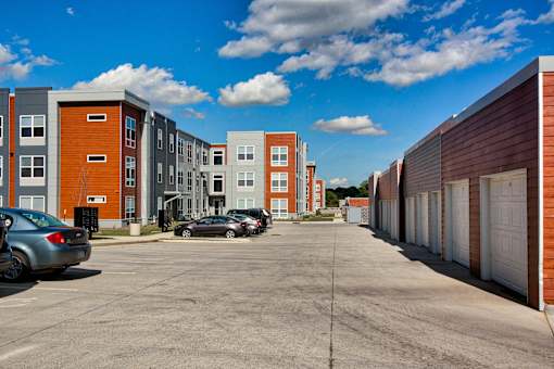 A parking lot in front of a row of apartment buildings.