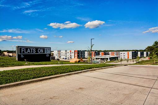 A sign that says Flats on 5th in front of a building.