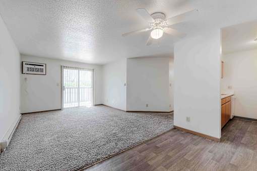 A spacious room with a ceiling fan and a window with blinds.