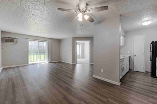 A spacious room with a ceiling fan and sliding glass doors leading to a balcony.