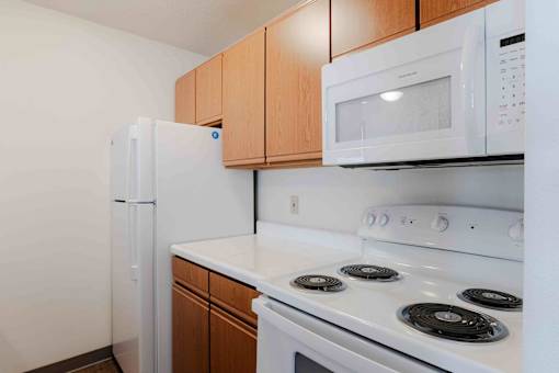 A white microwave oven is mounted above a white stove in a kitchen.