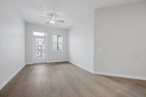 A room with a ceiling fan and a door leading to another room.