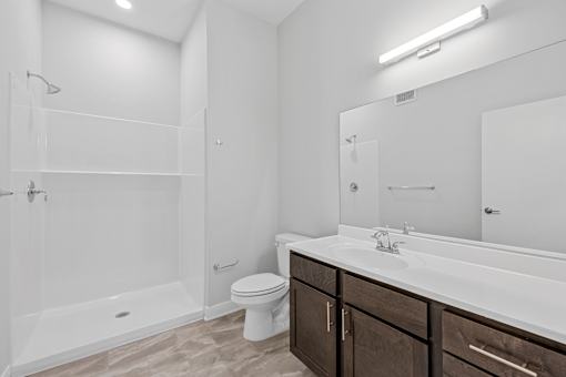 A white bathroom with a toilet, sink, and shower.