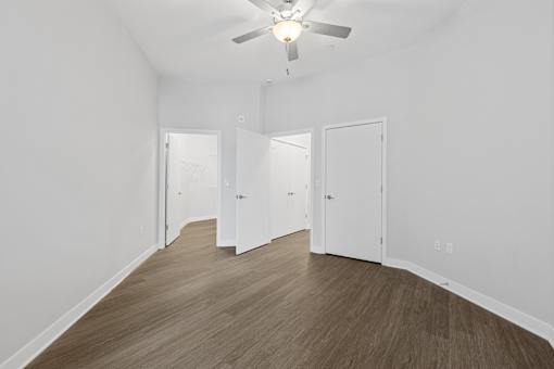 A room with a ceiling fan and wooden flooring.