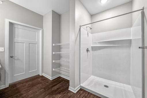 A white bathroom with a walk in shower and a towel bar at The Barclay Apartments, Altoona, IA