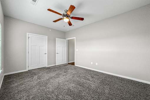 an empty room with carpet and a ceiling fan at The Barclay Apartments, Altoona