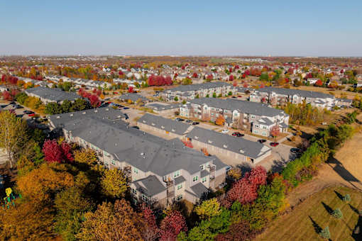 An aerial view of a residential area with apartment buildings and trees in autumn colors. at Stonegate Crossing Apartments, Clive, IOWA