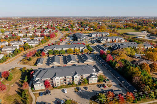 A bird's eye view of a residential area with houses and trees in autumn colors at Stonegate Crossing Apartments, IOWA