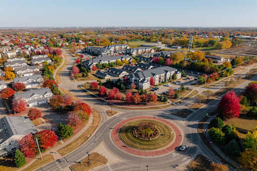 A roundabout in a suburban area with trees showing autumn colors. at Stonegate Crossing Apartments, Clive