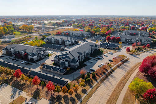 A large building surrounded by trees with autumn leaves. at Stonegate Crossing Apartments, IOWA