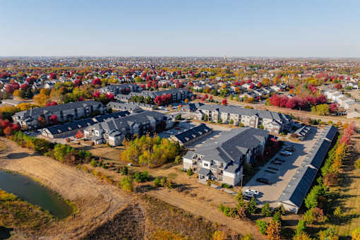 A bird's eye view of a residential area with houses and a parking lot at Stonegate Crossing Apartments, Clive