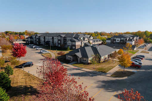 A parking lot with cars and apartment buildings in the background. at Stonegate Crossing Apartments, Clive, 50325