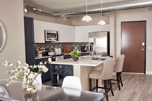 A kitchen with a table and chairs and a vase of flowers on the table.at Linc, Des Moines, IA 50309  