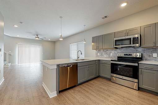 A modern kitchen with stainless steel appliances and wooden floors.at Linc, Des Moines  
