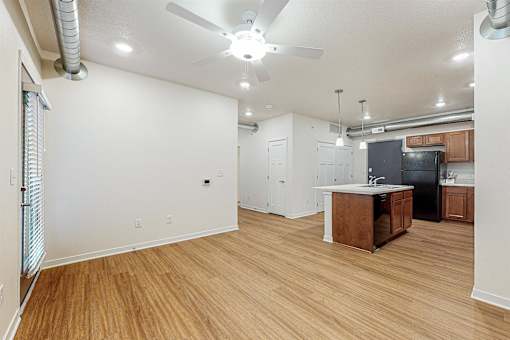 A kitchen with a black fridge and wooden floors at Melbourne Apartments, Des Moines, IA