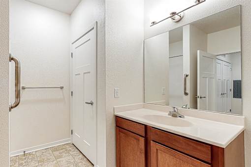 A bathroom with a sink, mirror, and a door at Melbourne Apartments, Georgia