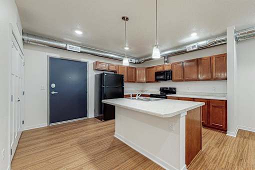 A kitchen with a white counter top and wooden cabinets at Melbourne Apartments, IA, 50320