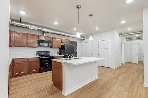A kitchen with a white island and wooden cabinets at Melbourne Apartments, IA, 50320