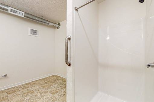 A bathroom with a walk-in shower and a tiled floor at Melbourne Apartments, Iowa, 50320