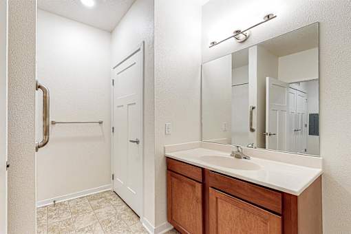 A bathroom with a sink, mirror, and a white door at Melbourne Apartments, Georgia