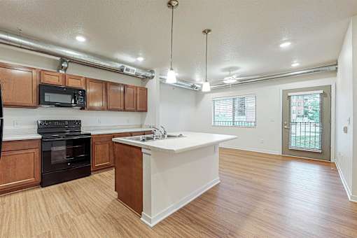 A kitchen with wooden cabinets and a white island at Melbourne Apartments, Des Moines