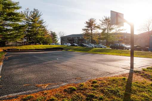 A parking lot with a basketball hoop in the background. at Rosemont Place Apartments, Iowa, 50320