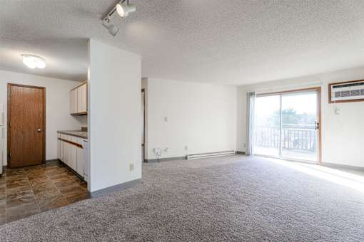 A spacious living room with a kitchen area in the background at Rosemont Place Apartments, Des Moines, IA