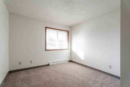 A room with a window and carpeted floor at Rosemont Place Apartments, Iowa, 50320