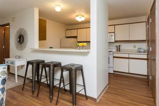 a living room with three bar stools and a kitchen at Rosemont Place Apartments, Des Moines, 50320
