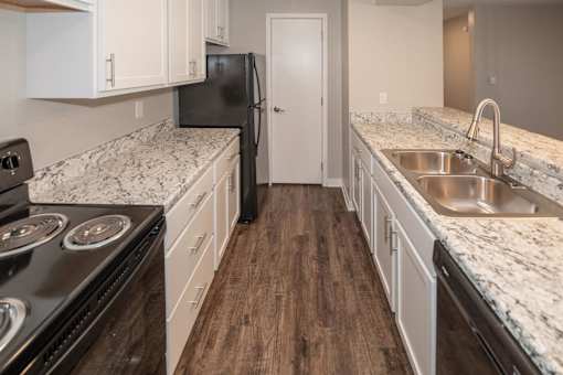 a kitchen with white cabinets and marble counter tops and a black refrigerator at Rosemont Place Apartments, Des Moines, Iowa