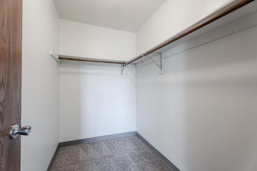A small, empty room with a brown door and a grey carpet. at Rosemont Place Apartments, Iowa, 50320