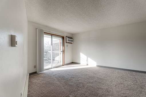 A room with a carpeted floor and a sliding glass door leading to a balcony at Rosemont Place Apartments, Des Moines, Iowa